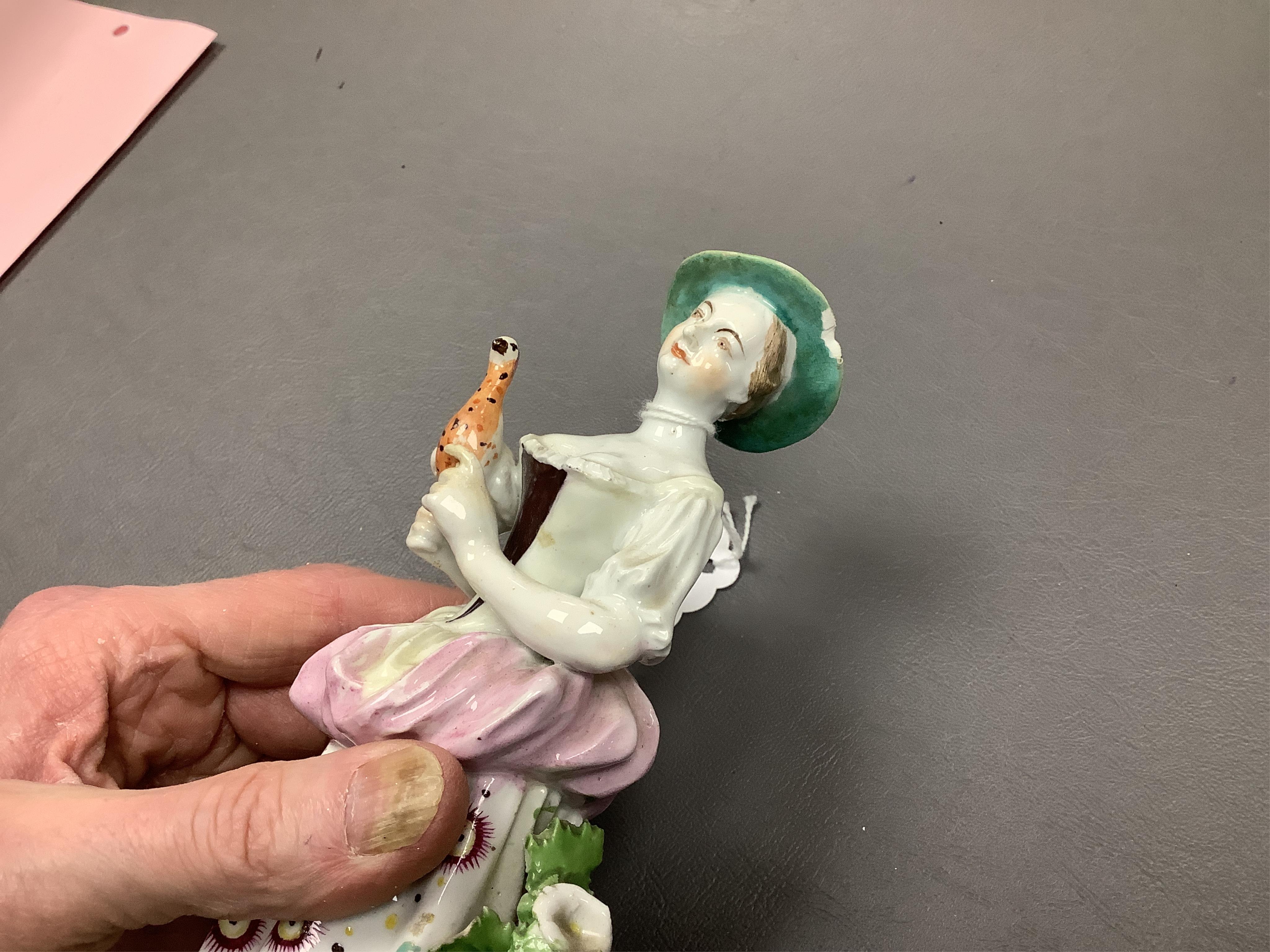 A Derby porcelain figure of a lady holding a bird, c.1760-65 and a Derby porcelain figure of a gentleman fruit seller, largest 24cm high (2)